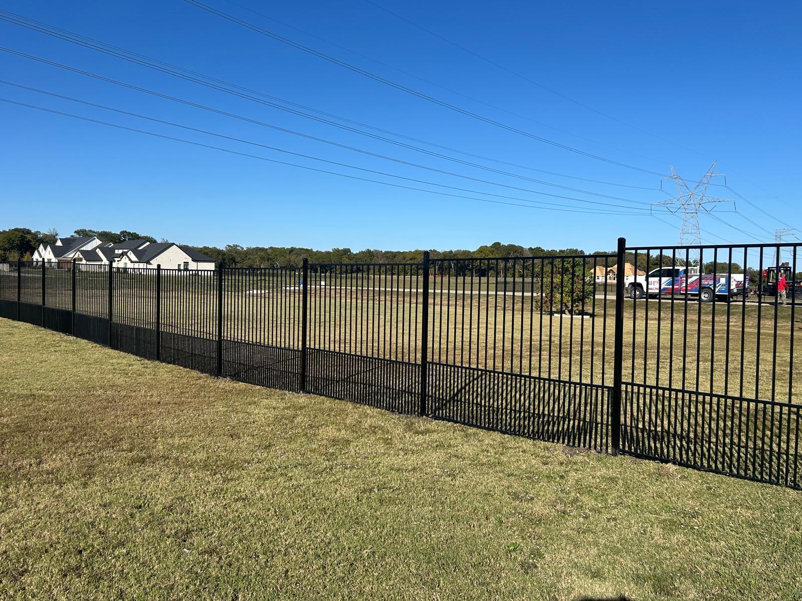 Black aluminum commercial fence running the length of a property boundary in DFW