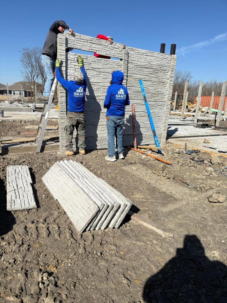 Installation crew setting precast concrete fence panels with a boom truck
