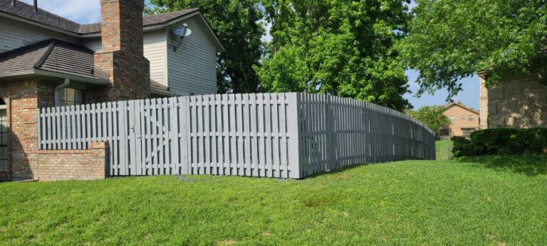 Gray painted wood picket fence and matching gate at a corner yard