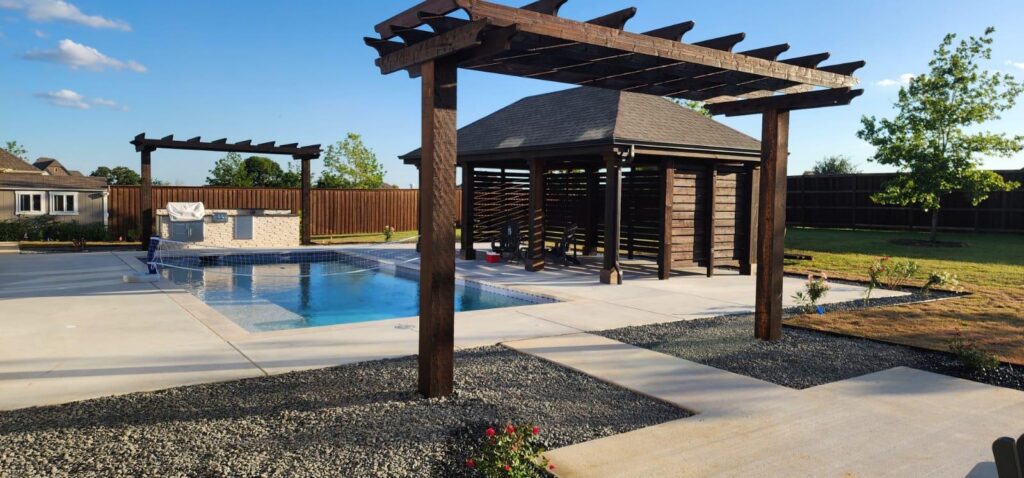 Open pavilion with hip roof shading a poolside outdoor kitchen and seating area