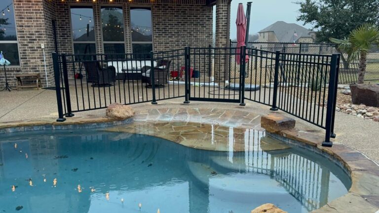 Black metal pool fence around a backyard swimming pool and patio