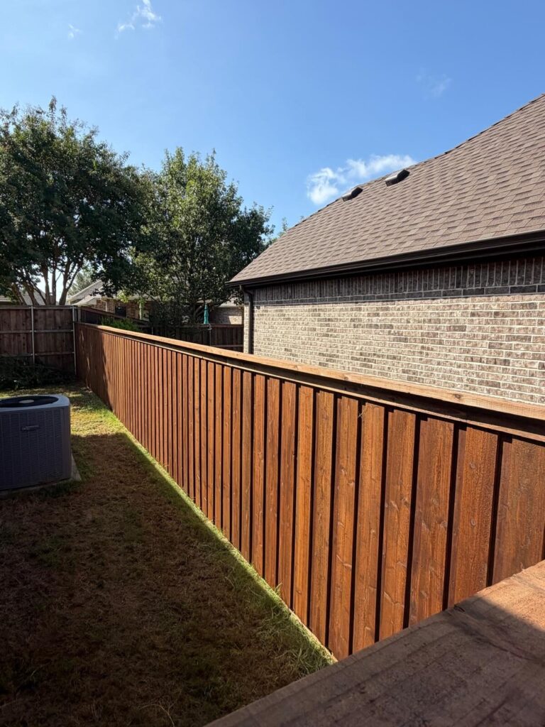 New stained cedar board-on-board privacy fence along a brick home side yard