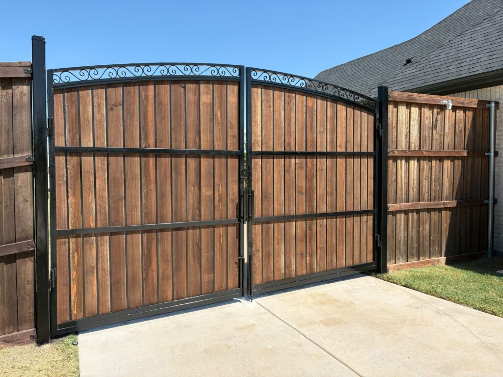Steel-framed cedar double drive gate with scroll arch tying into a board-on-board cedar fence