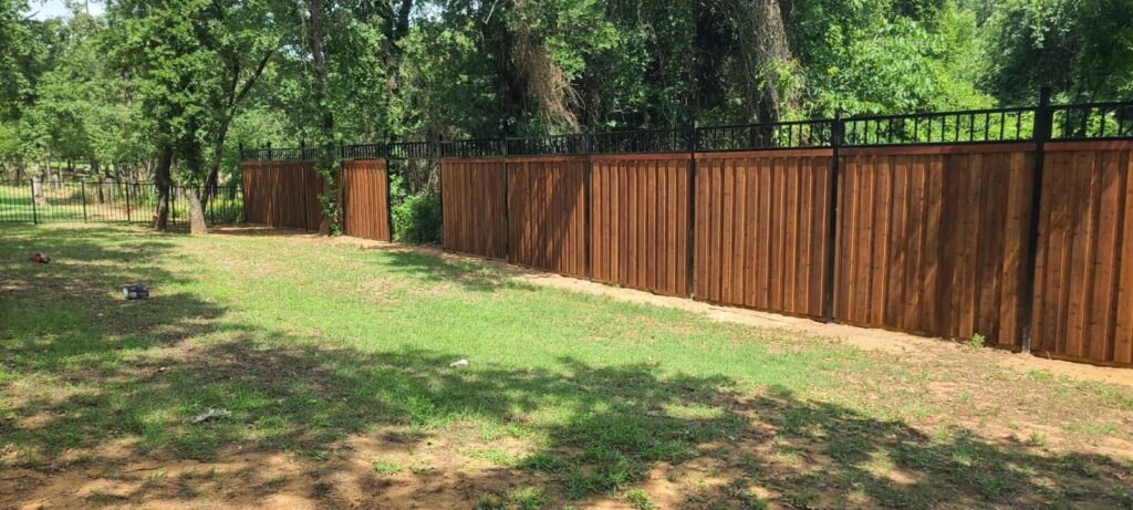 Cedar fence with black iron topper enclosing a grassy backyard