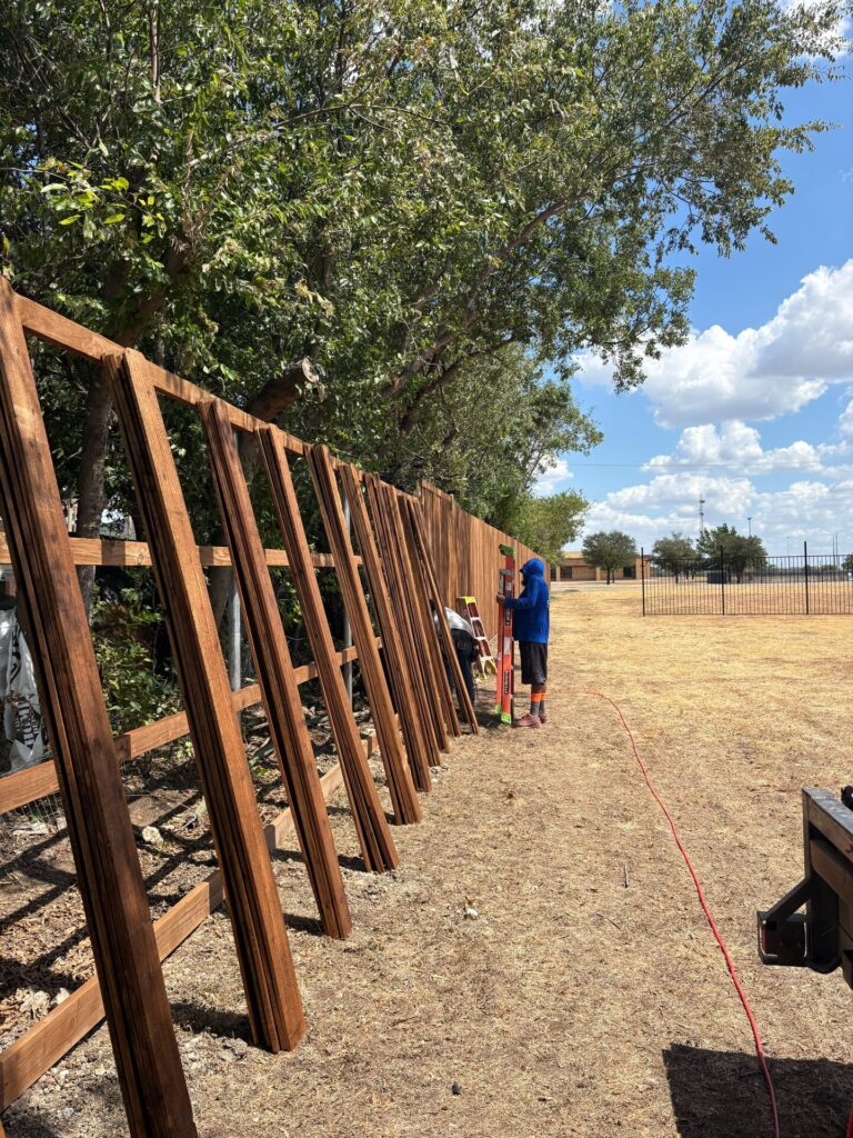 Crew framing a new cedar privacy fence with posts and rails set along a property line