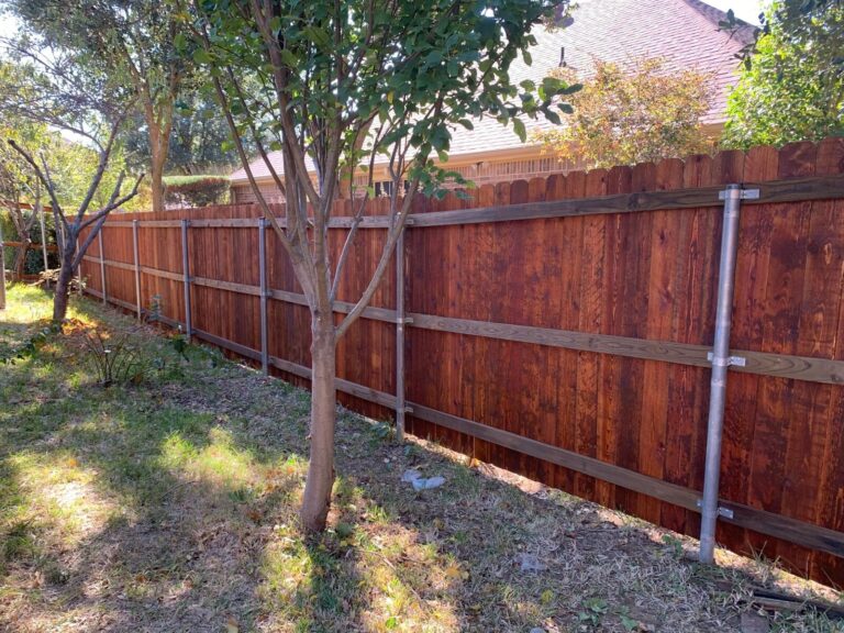 Rear side of a stained cedar fence on galvanized steel posts