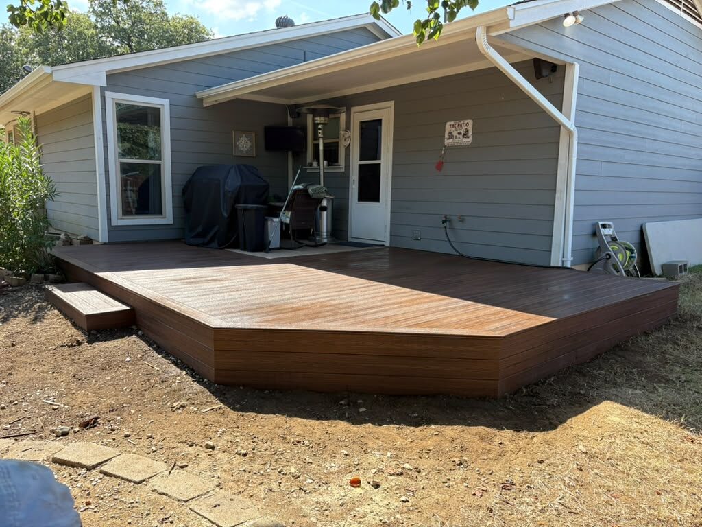New ground-level composite deck with angled corner extending a covered back patio