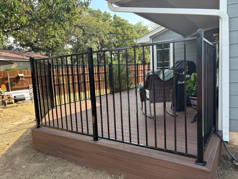 Black metal railing on a composite deck corner beside a covered patio