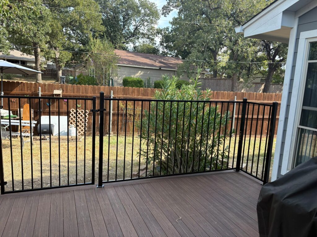 Black metal deck railing with a walk-through gate overlooking the backyard