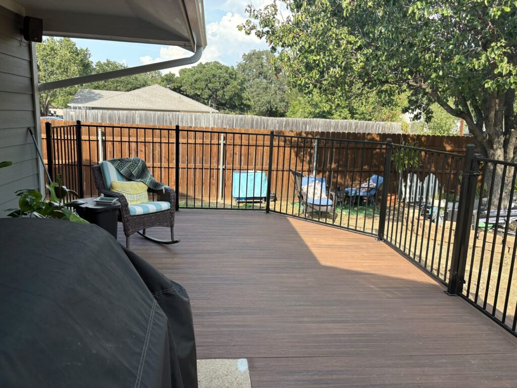 View across a railed composite deck toward the backyard and cedar fence