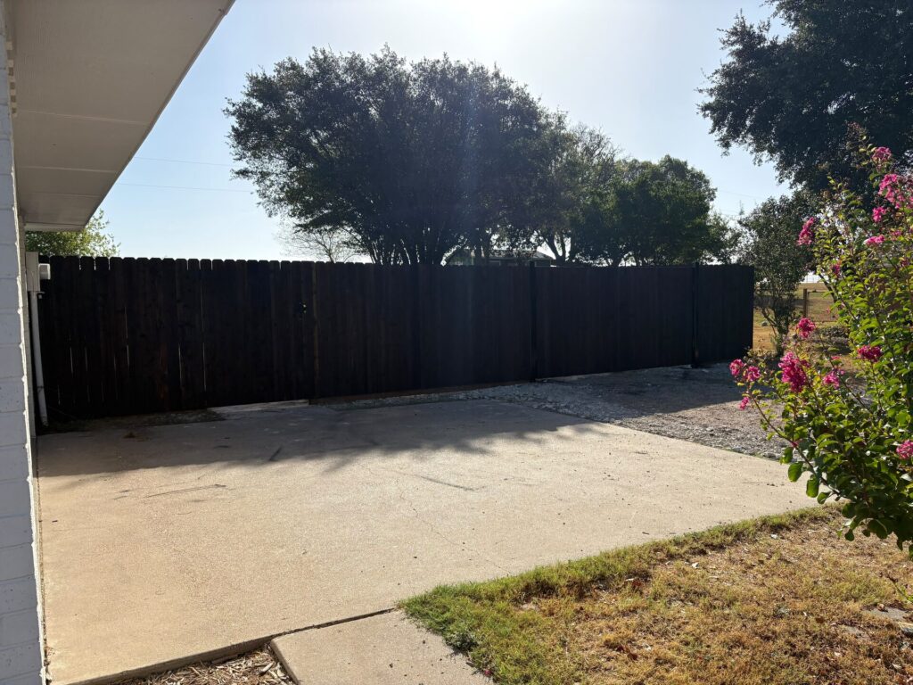 Dark-stained wood privacy fence seen from a concrete back patio