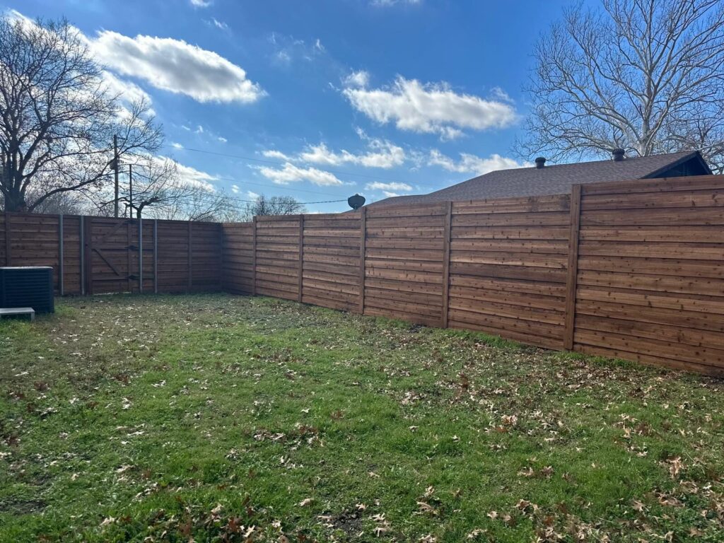 Modern horizontal cedar fence enclosing a backyard lawn