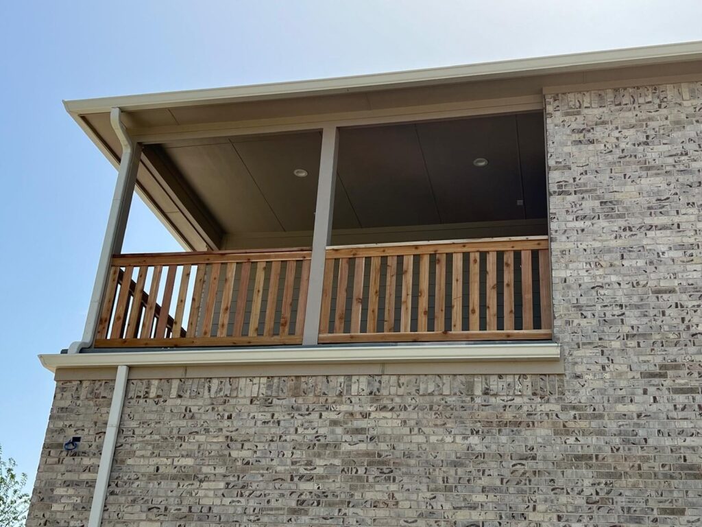 Wood balcony railing on a second-story covered porch