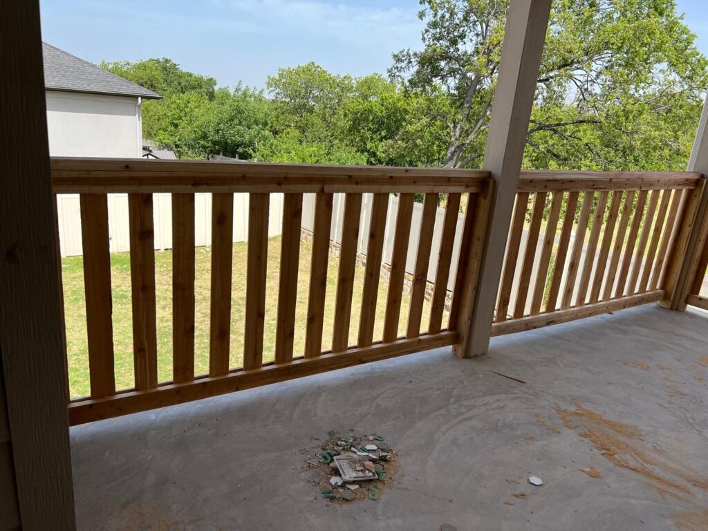 Wood railing on a covered patio overlooking a backyard