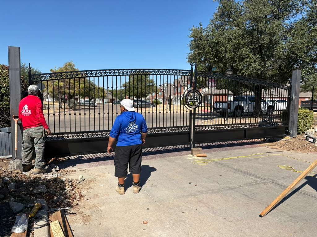 Grace Construction crew installing a wide wrought iron entry gate with scroll detail